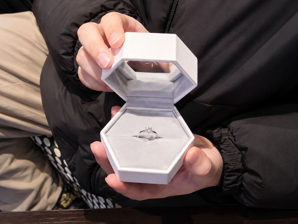 六角形のリングケースを開いて婚約指輪を見せるお客様